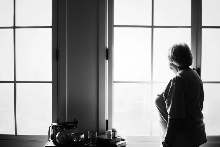 Mujer tercera edad mirando por la ventana en blanco y negro