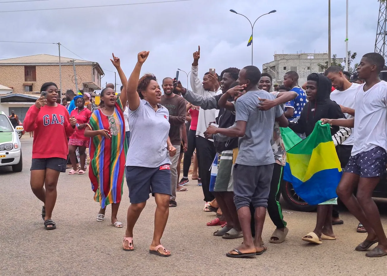 La gente muestra la bandera nacional de Gabón mientras se reúnen para celebrar en las calles de Akanda, Gabón, 30 de agosto d